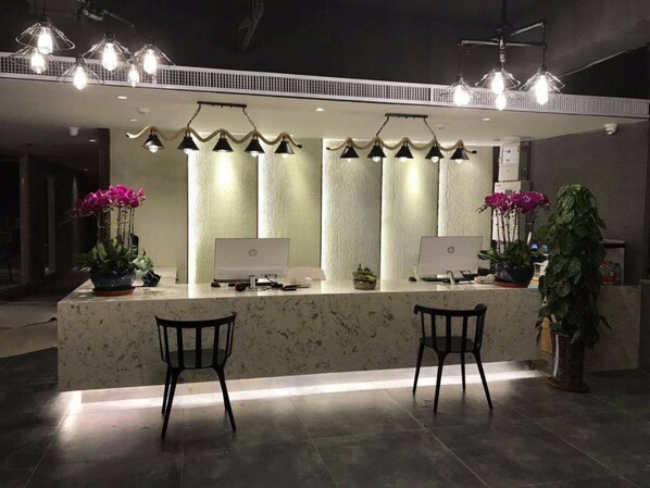 A reception area with two HP desktop computers, two chairs, and decorative lighting. - Manchen Hotel (Xi'an)