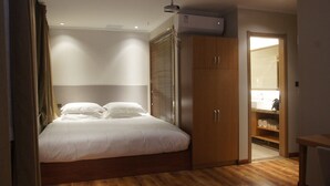 A bedroom with a wooden bed, a wardrobe, and a bathroom visible through an open door. - Manchen Hotel (Xi'an)