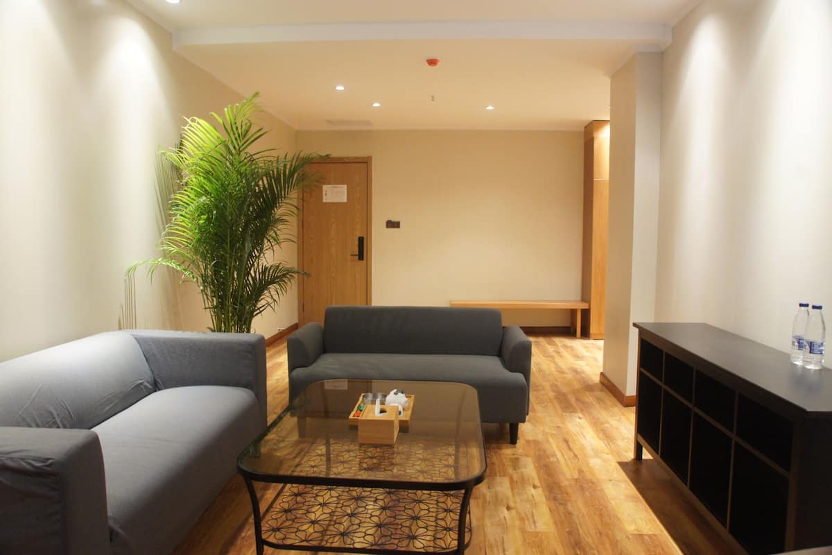 Uma sala de estar moderna com um sofá cinzento, uma mesa de centro de vidro e um banco de madeira.