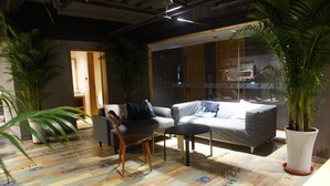 A modern living room with a sofa, chairs, and a coffee table. There are potted plants and a large window. - Manchen Hotel (Xi'an)