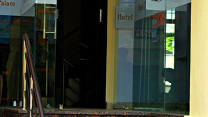 Entrada de hotel con un letrero que dice 'Welcome', puertas de cristal y una escalera de mármol.