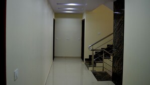 Un pasillo con una escalera, luces empotradas en el techo y un muro de mármol.