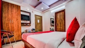 Un dormitorio con una cama grande, un armario de madera, un escritorio y un televisor montado en la pared.