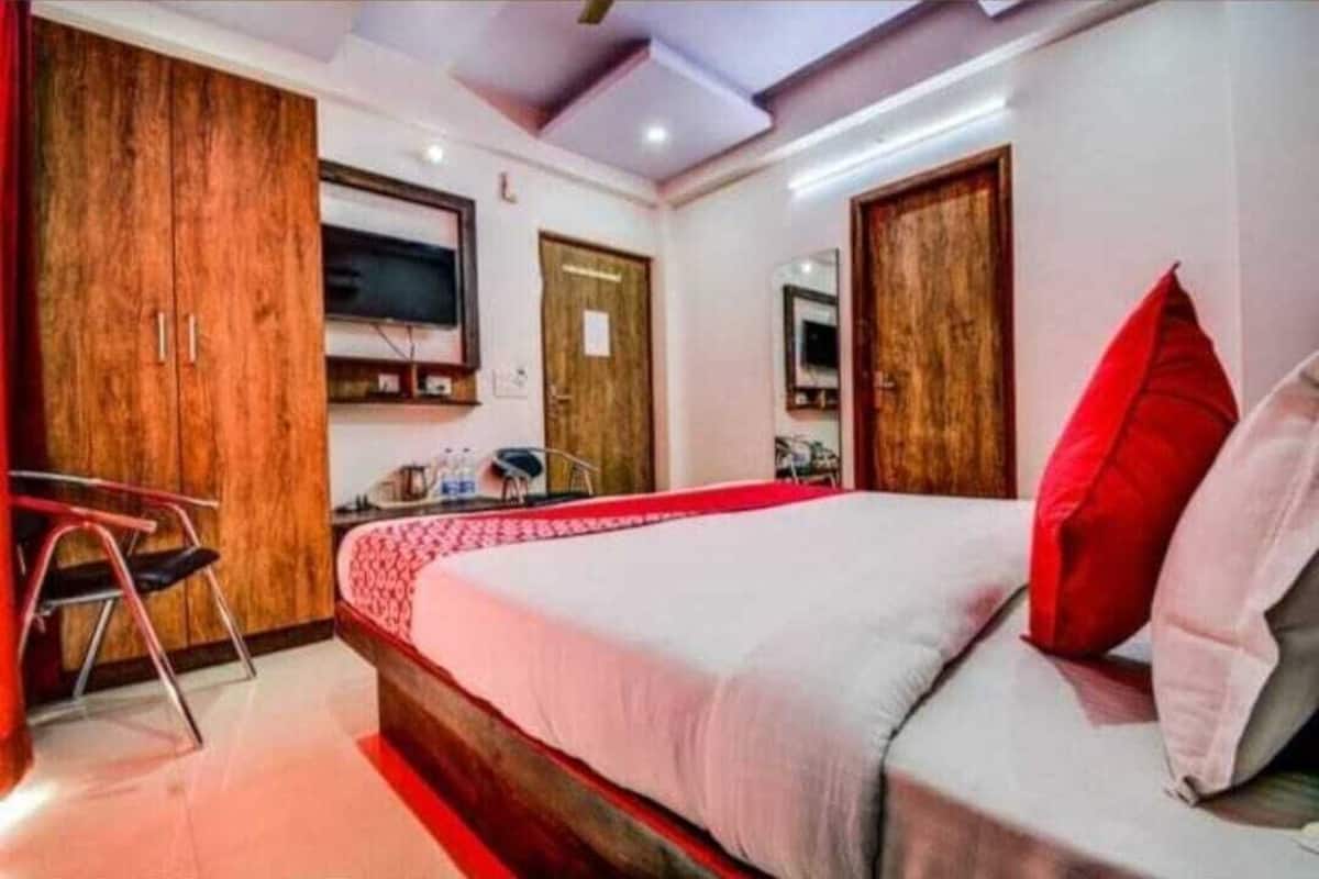 Un dormitorio con una cama grande, un armario de madera, un escritorio y un televisor montado en la pared.