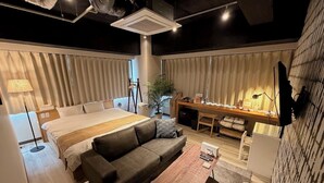 Een moderne hotelkamer met een groot bed, een bank, een bureau en een bijzettafeltje.