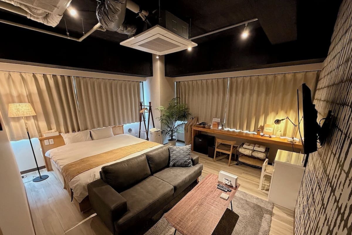 Una habitación de hotel moderna con una cama grande, un sofá, un escritorio y una mesita.