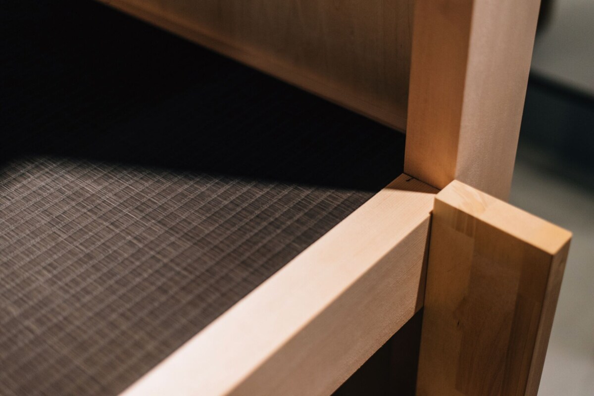 A close-up of a wooden chair with a textured fabric seat.