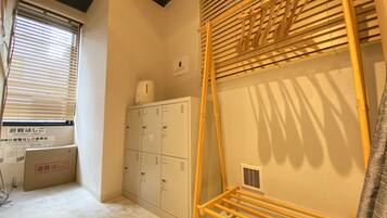 A room with a wooden ladder, a set of lockers, and a window with blinds.
