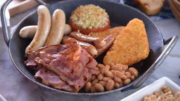 A plate of food including sausages, bacon, beans, and a fried item.