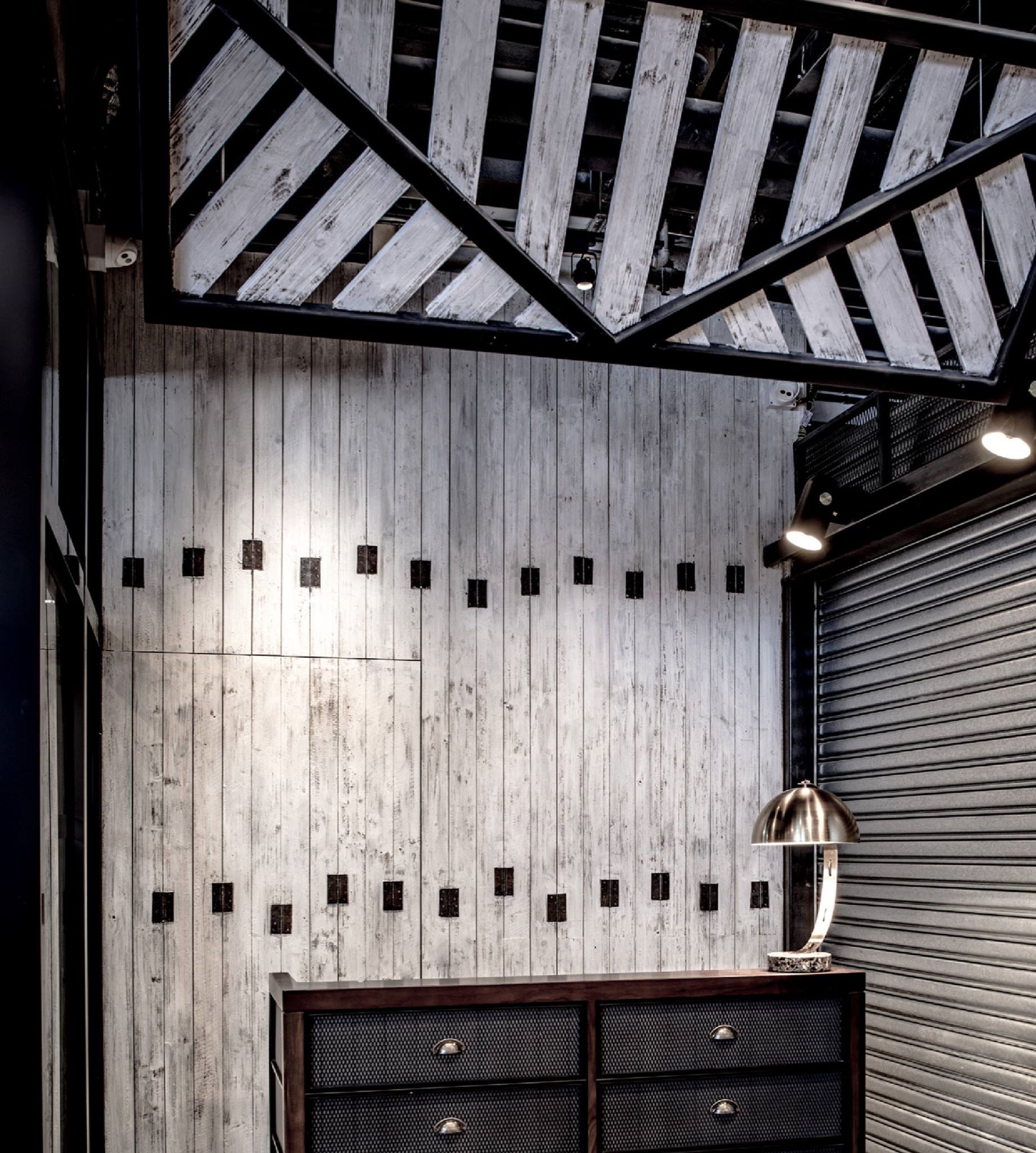 Een kamer met een houten plafond, een raam met metalen frame en een gesloten luik.