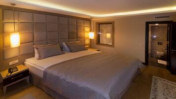 A modern hotel room with a large bed, a bedside table with a phone, and a wall-mounted light fixture.