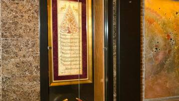 A framed document with a decorative emblem in a hallway.