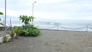 A sandy beach with a rope barrier, a street lamp, and some greenery. - Nipa Hut Villa by AMCO Extension (Baler)