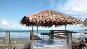 A beachside gazebo with a thatched roof, wooden benches, and a view of the ocean. - Nipa Hut Villa by AMCO Extension (Baler)