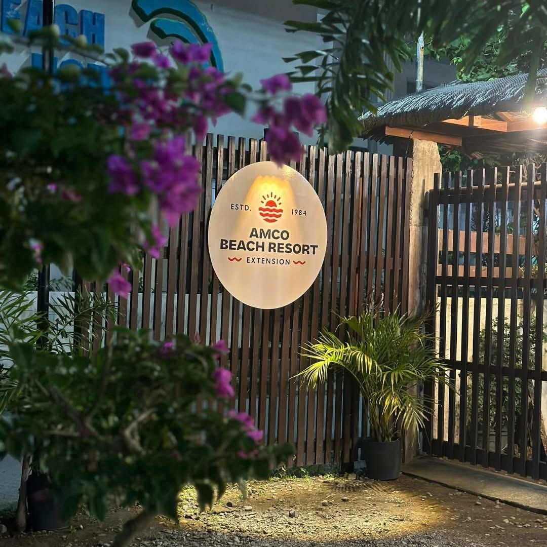 A sign for AMCO Beach Resort Extension with a sun logo, established in 1984.