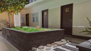A hotel lobby with a water feature, stone pathway, and doors numbered 103 and 104. - The Homee Cozy Modern Studio Apartment (Ho Chi Minh City)