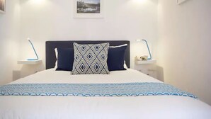 A neatly made bed with a patterned bedspread, two bedside lamps, and a framed picture on the wall. - Chiado Blue by Homing (Lisbon)