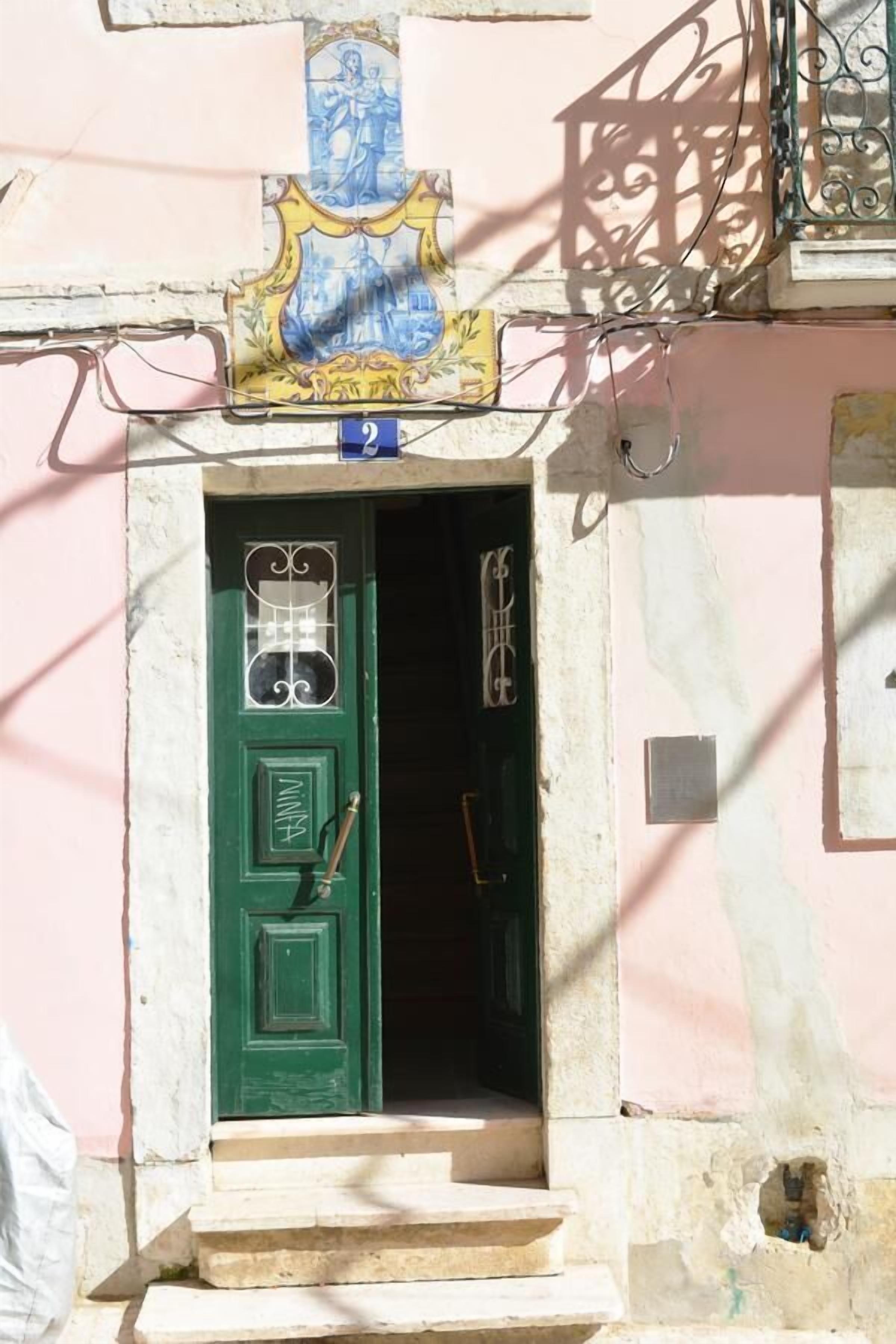 Una puerta verde con un pequeño ventanal y un timbre.