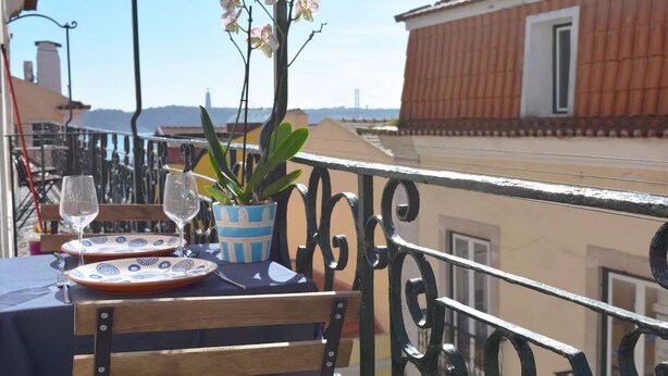 A balcony table with a potted plant, two wine glasses, and a plate. - Chiado Blue by Homing (Lisbon)
