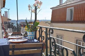 A balcony table with a potted plant, two wine glasses, and a plate. - Chiado Blue by Homing (Lisbon)