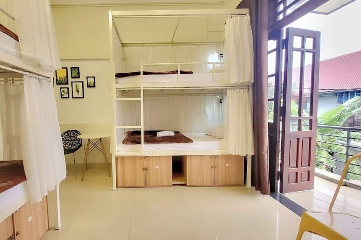 A dormitory room with bunk beds, a small table, and a chair.