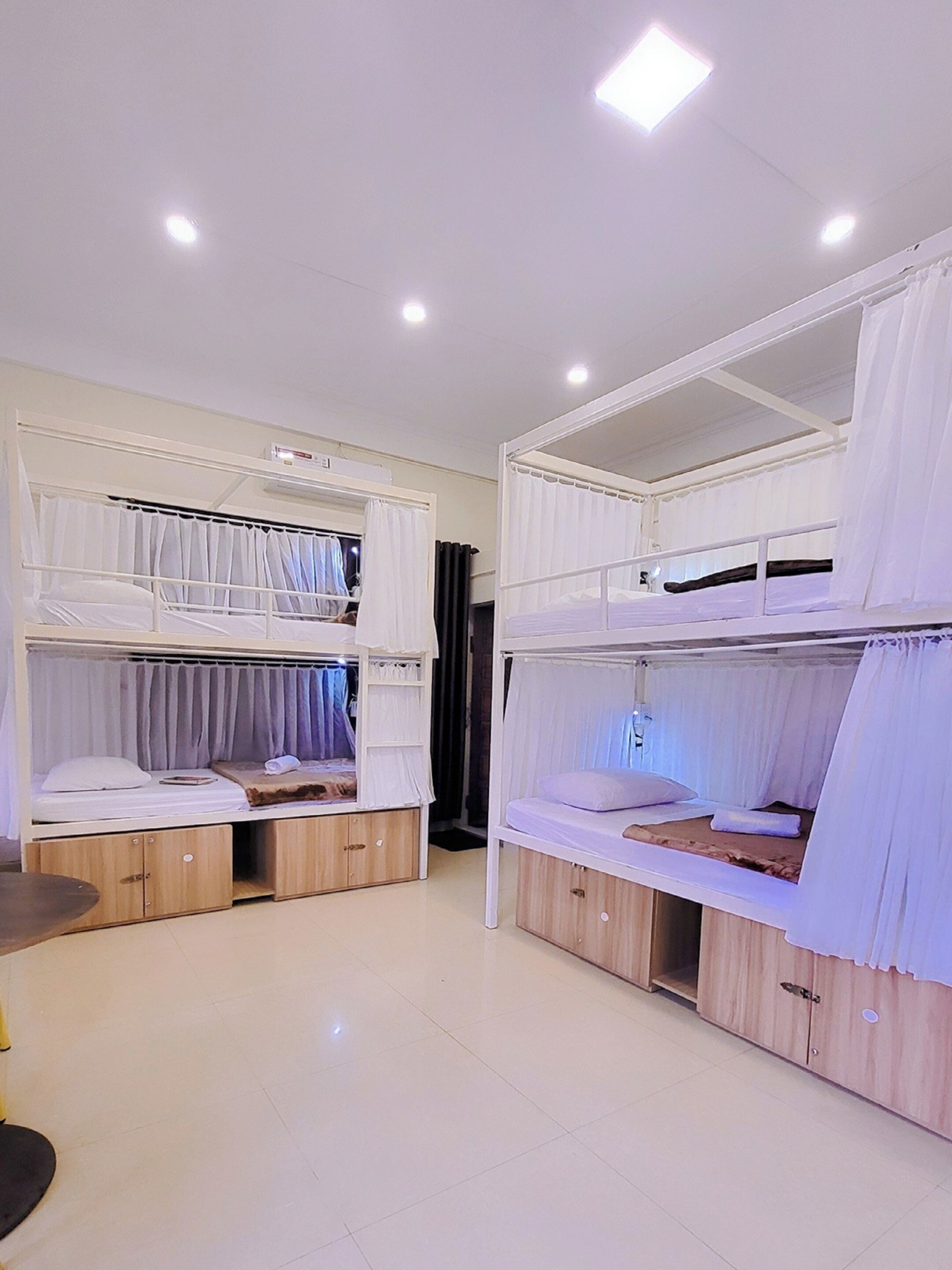 Une pièce avec des lits superposés, des armoires en bois et un luminaire au plafond.