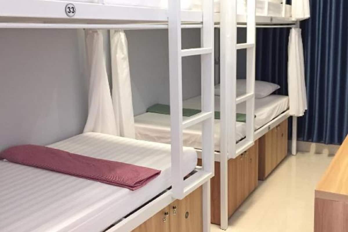 A bunk bed room with a white air conditioning unit above and a wooden desk to the right.