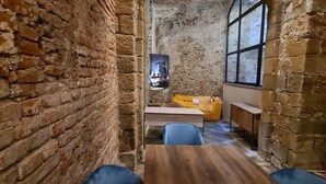 Una habitación pequeña con paredes de piedra, una mesa de madera y sillas tapizadas en azul.