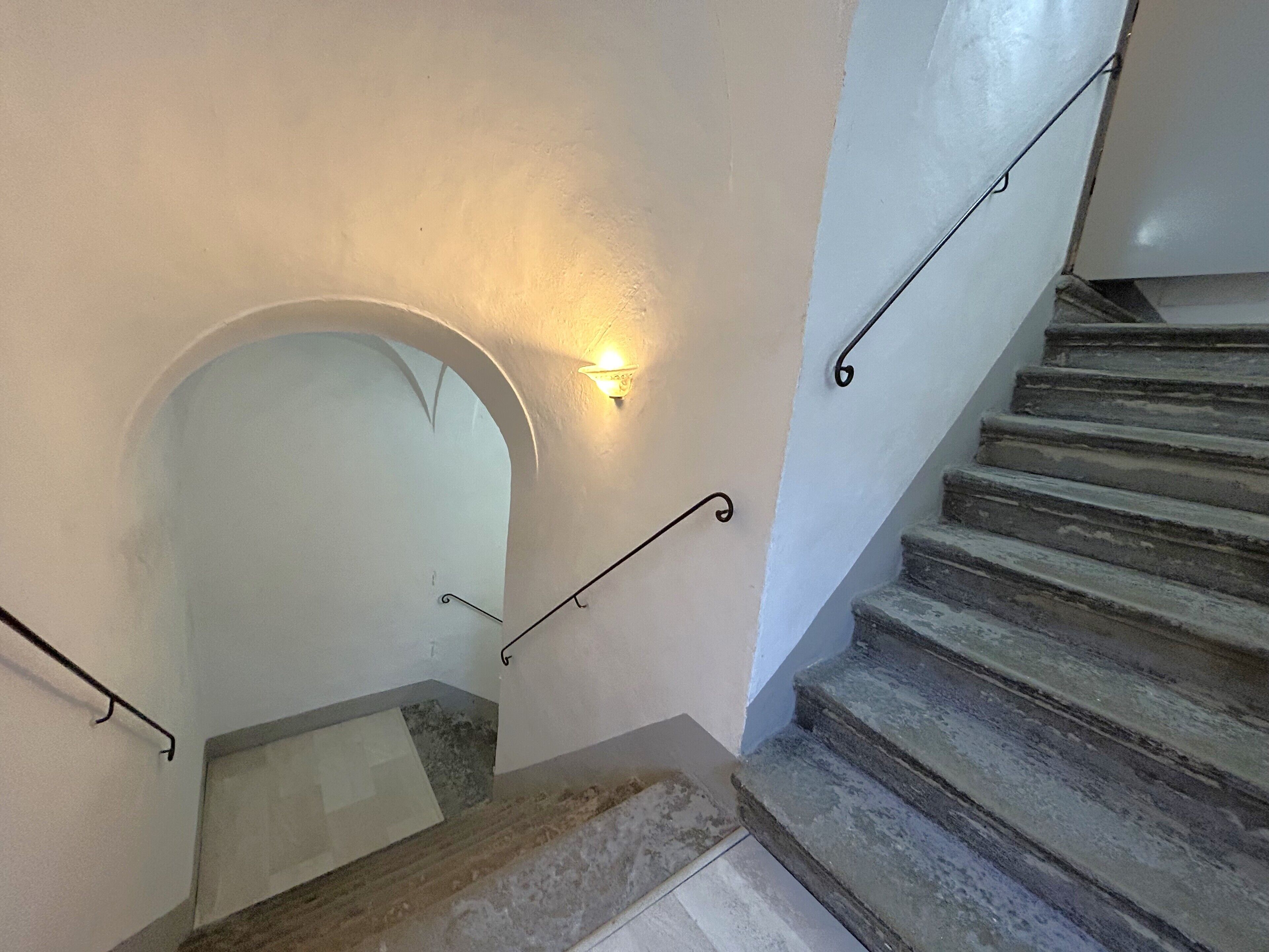 Una escalera de piedra con barandales de metal que conduce a un piso superior.