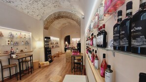 Interior de un hotel boutique con pisos de madera, un arco central y estanterías que exhiben diversas botellas y cajas.