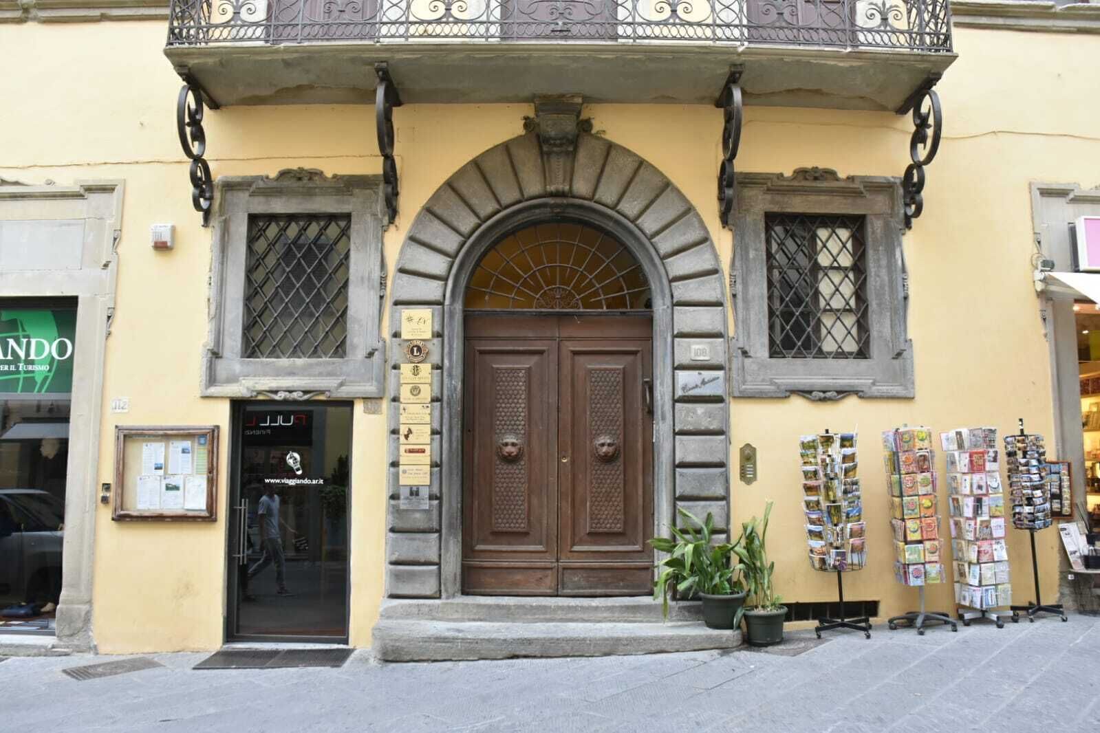 Un edificio con un'ampia porta centrale, due finestre più piccole e un balcone con ringhiere in ferro decorativo.
