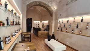 Una habitación amplia con suelo de madera, una mesa larga de madera y varias sillas. Estantes en las paredes exhiben diferentes botellas y tarros.