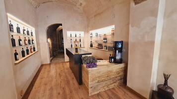 A wine tasting room with wooden floors, a central tasting table, and shelves of wine bottles on either side.