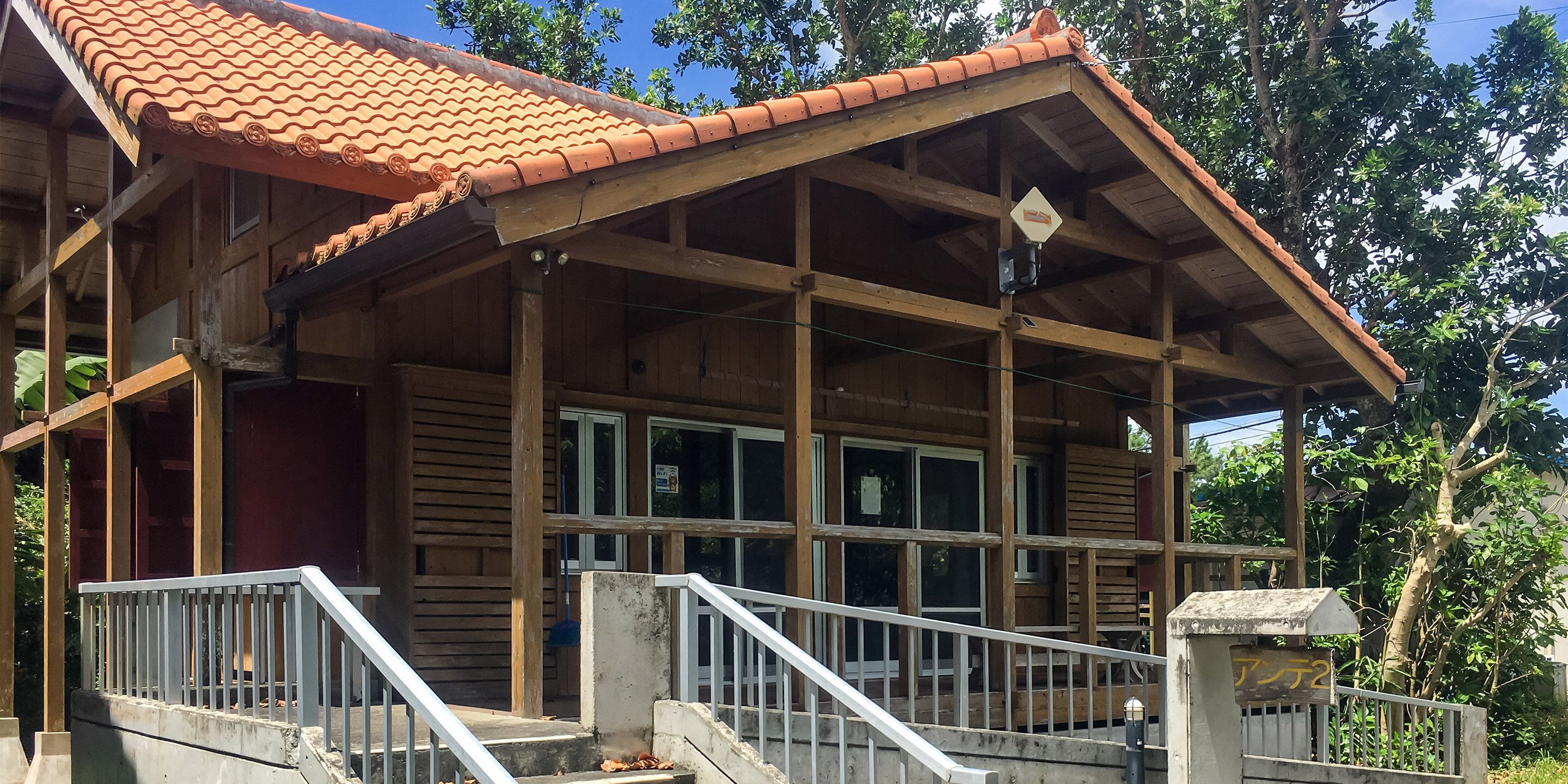 A wooden building with a tiled roof, a covered porch, and a gated entrance.