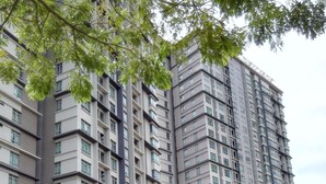 Un edificio residencial de gran altura con varios balcones, un paseo techado y abundante vegetación.