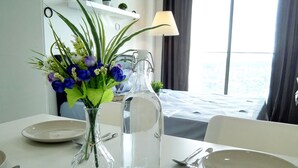 Mesa de comedor dispuesta con platos, cubiertos, un florero con flores y una botella de agua.