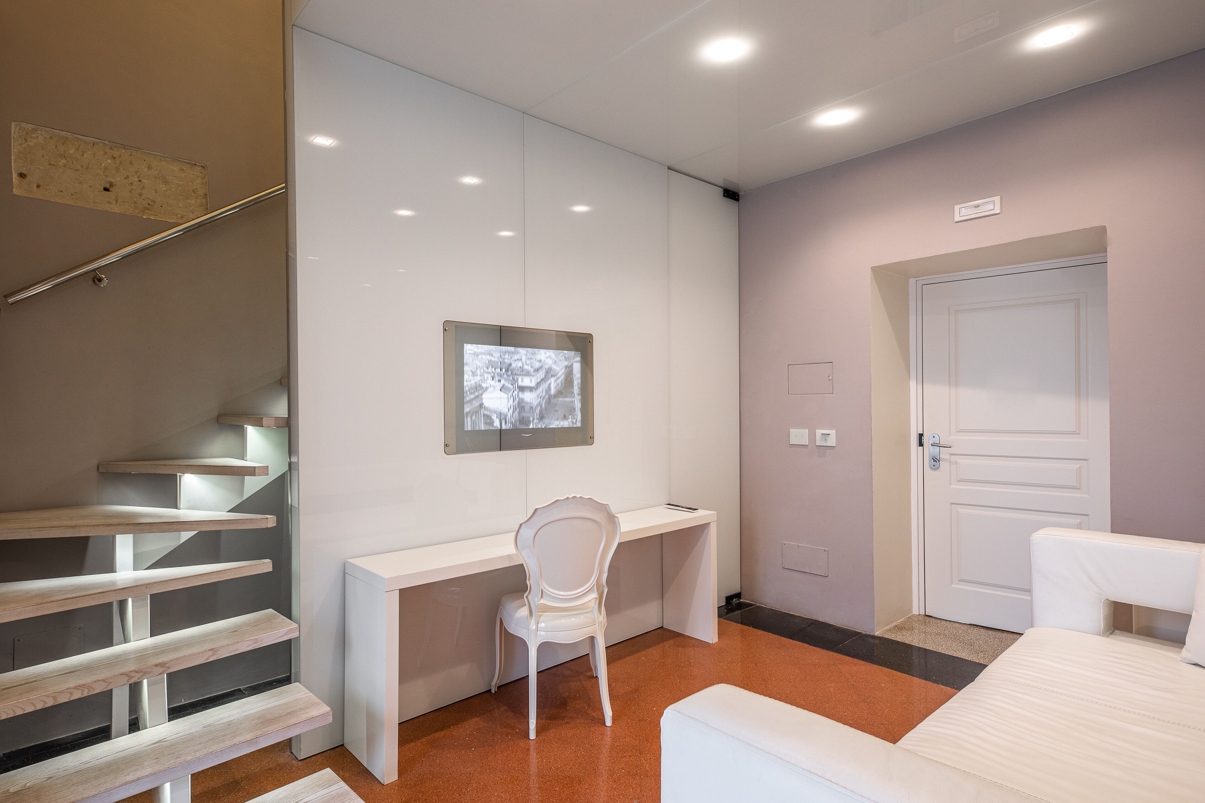 Una habitación de hotel moderna con una escalera, un escritorio, una silla y una cama.