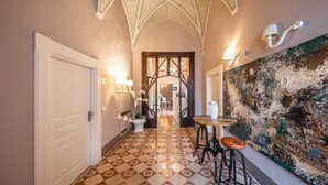 Um corredor com piso estampado, uma porta branca e um painel de parede com um mural texturizado.