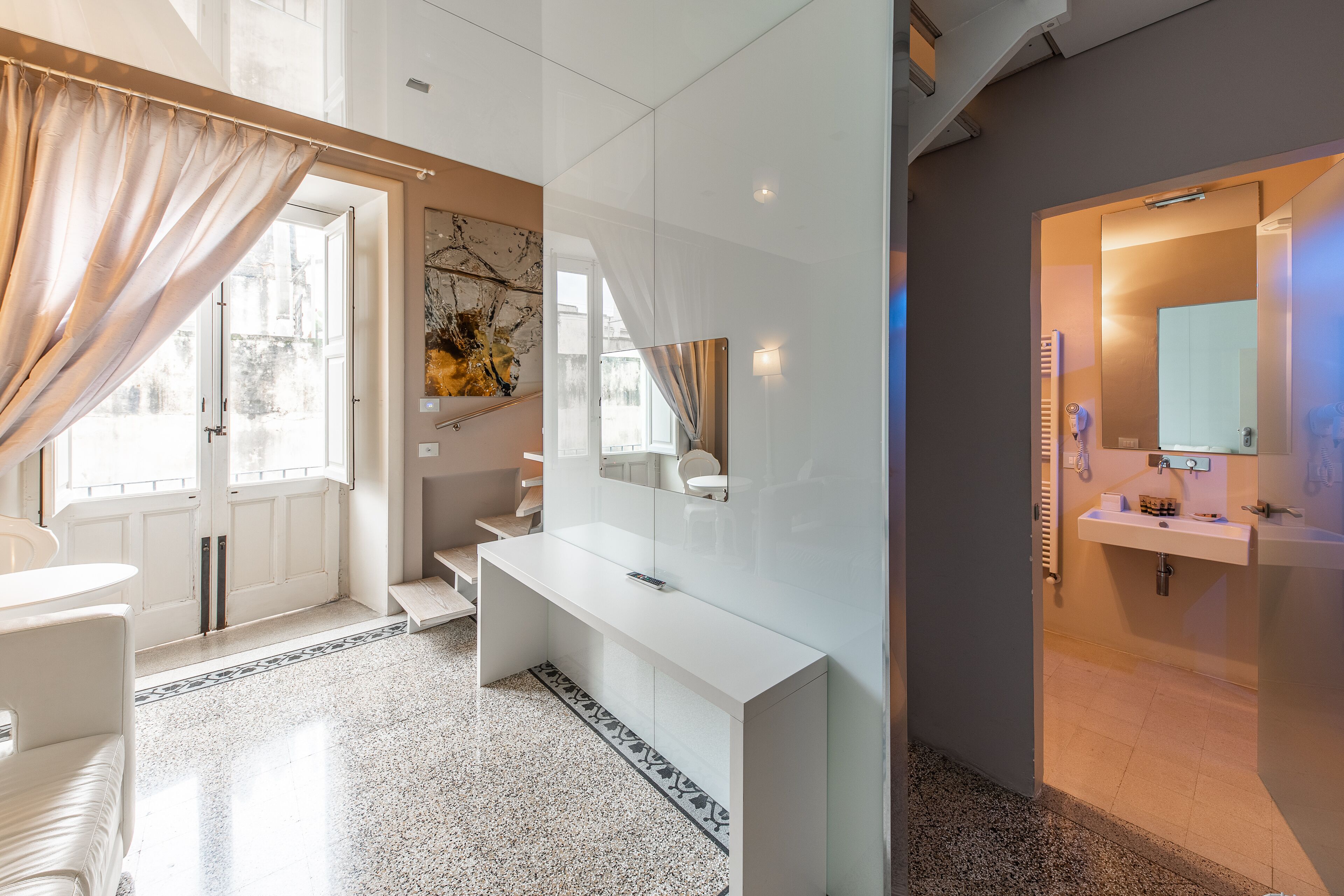 A modern bathroom with a white vanity, a large mirror, and a separate sink area.