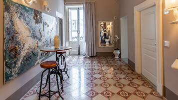 Un pasillo con piso de baldosas estampadas, un cuadro abstracto grande a la izquierda y una puerta a la derecha.