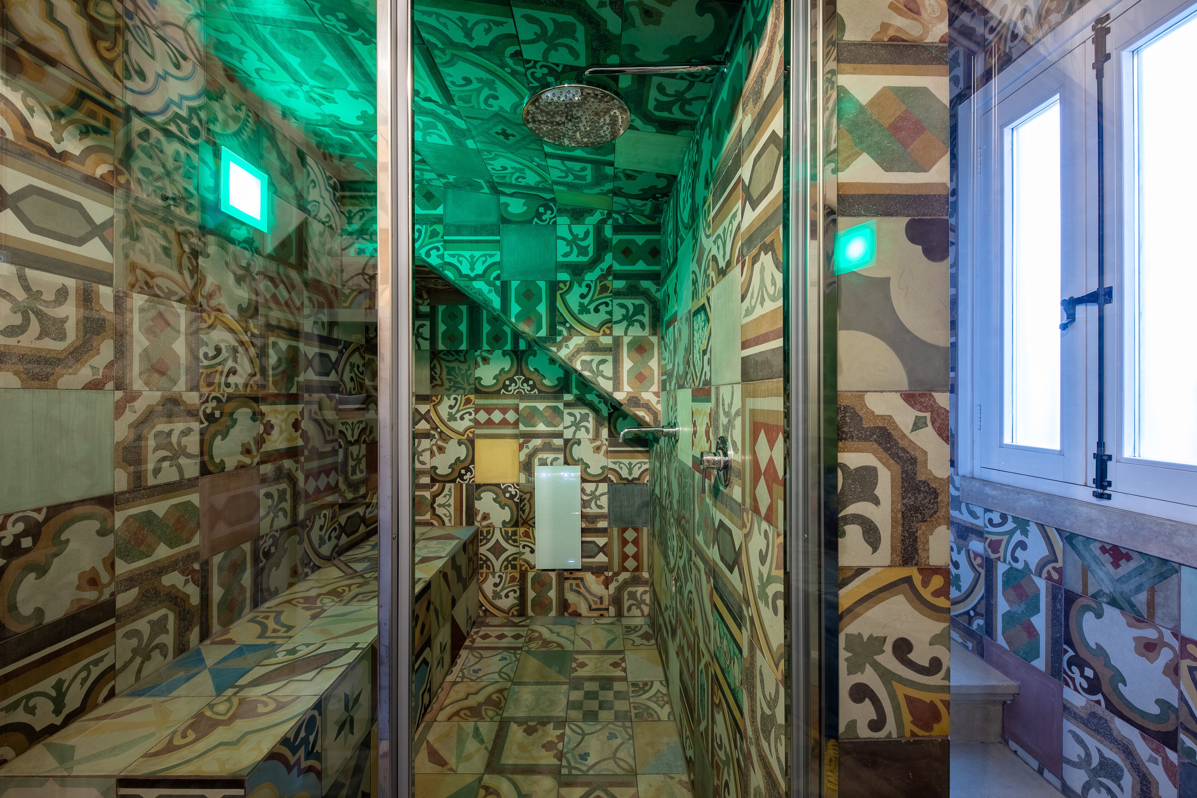 A narrow hallway with patterned walls and a tiled floor, leading to a bathroom with a toilet and a sink.