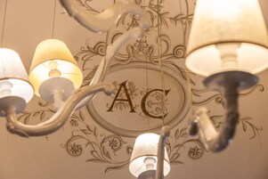 Un candelabro con múltiples lámparas y un techo decorativo con motivos florales y las letras 