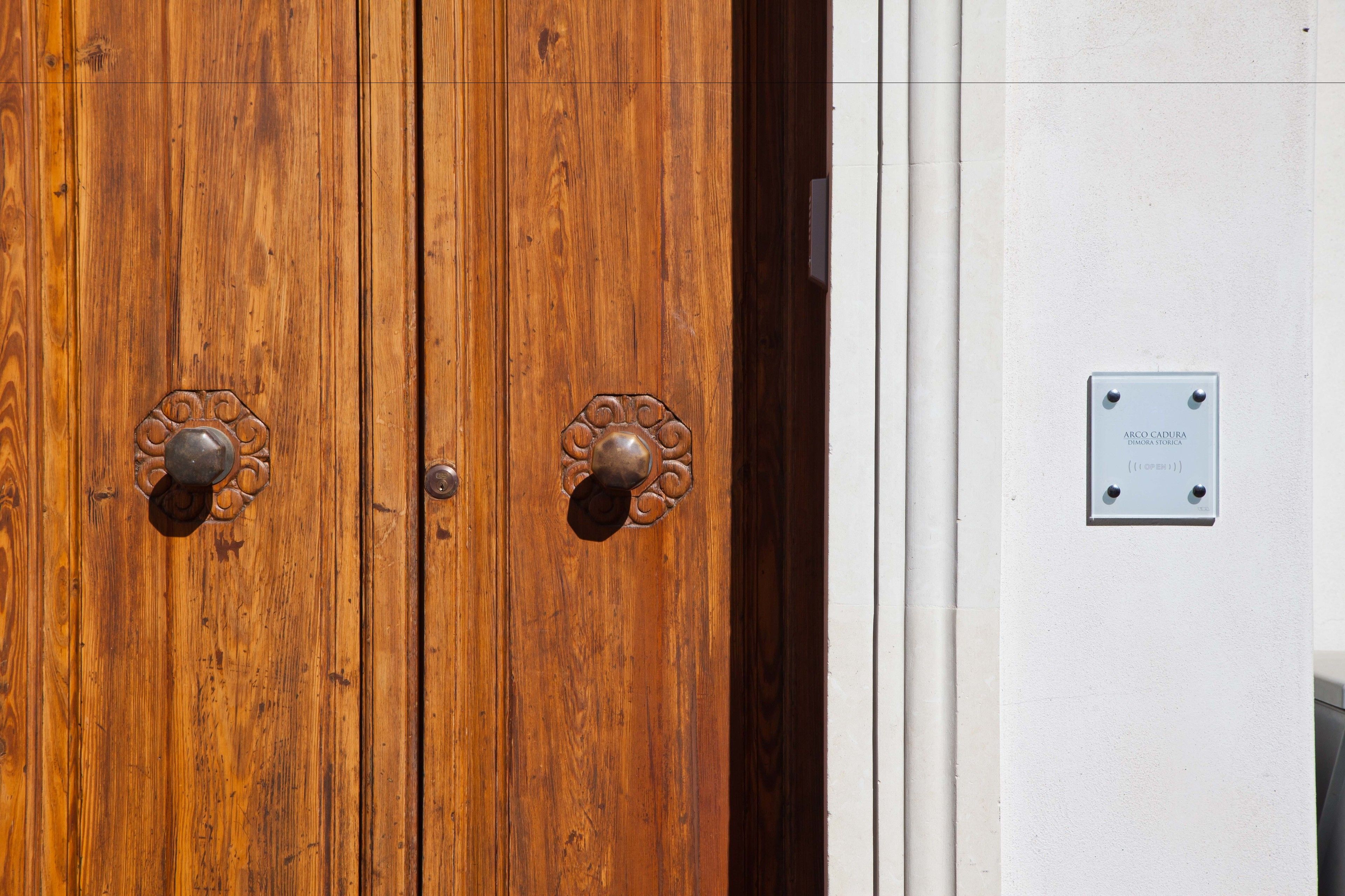 A wooden double door with ornate metal handles and a plaque on the adjacent wall.