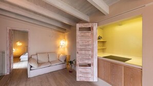 Uma sala de estar aconchegante com piso de madeira, um sofá bege e um armário de madeira com bancada amarela.