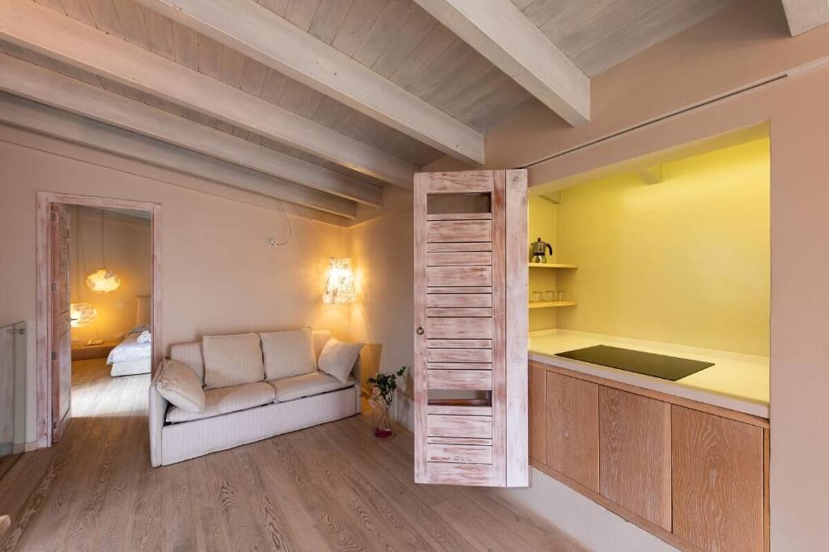 Un salon chaleureux avec un plancher en bois, un canapé beige et un meuble en bois surmonté d’un comptoir jaune.