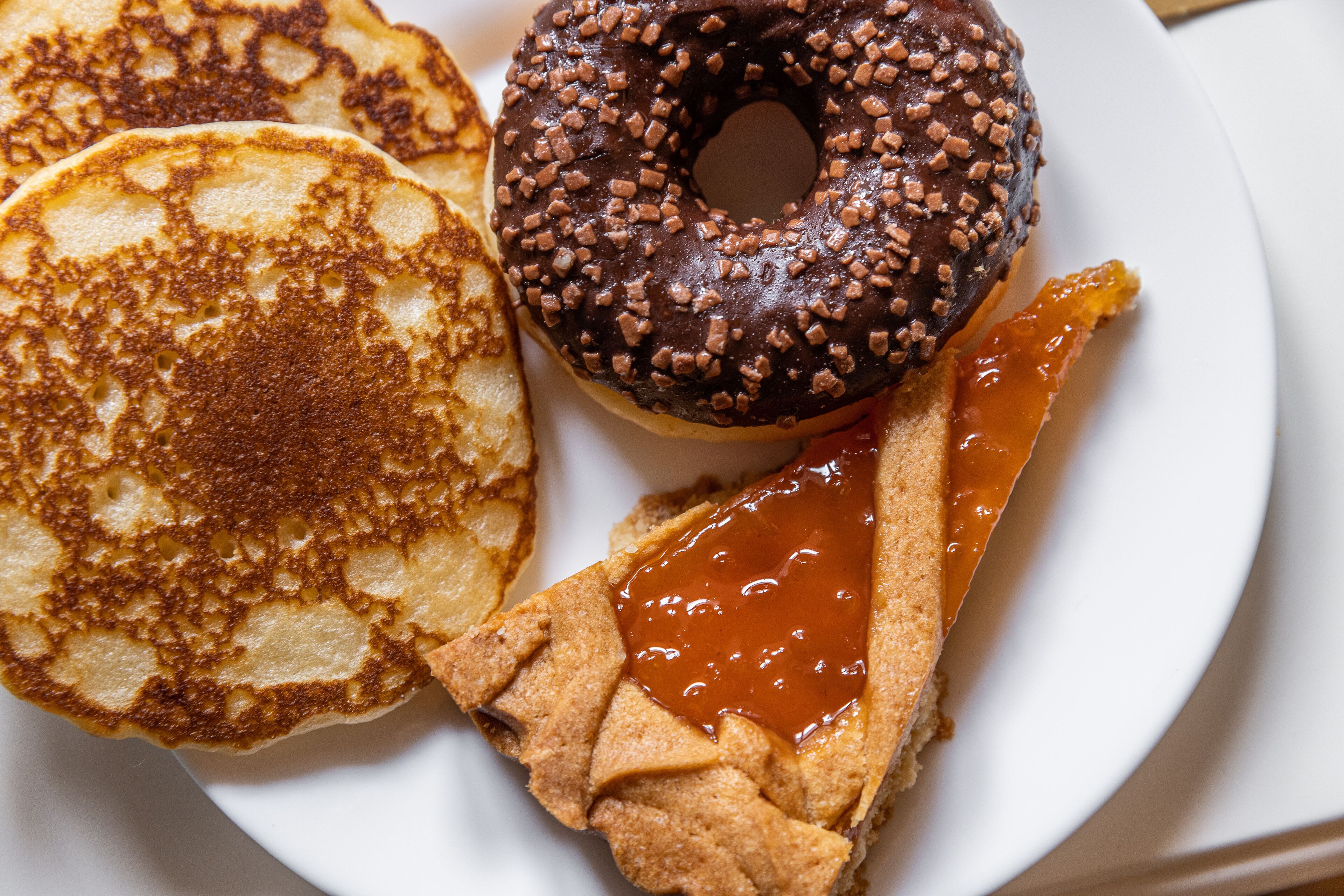 Um prato com panquecas, um donut e uma fatia de torta.