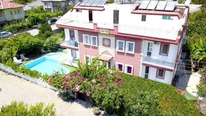 Un edificio de varios pisos con piscina, rodeado de vegetación y otras edificaciones residenciales.