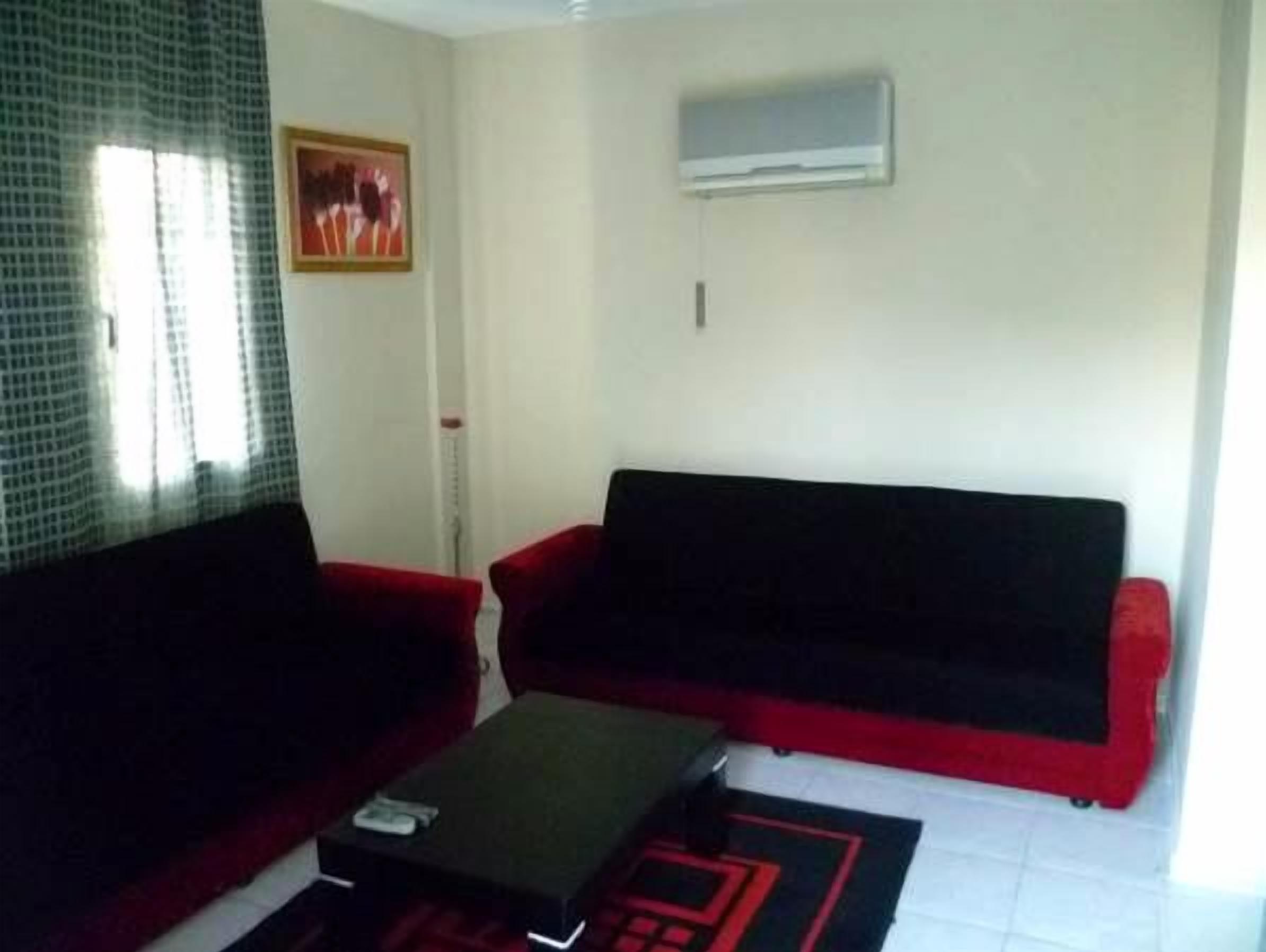 A living room with a red sofa, a black coffee table, and a patterned rug.