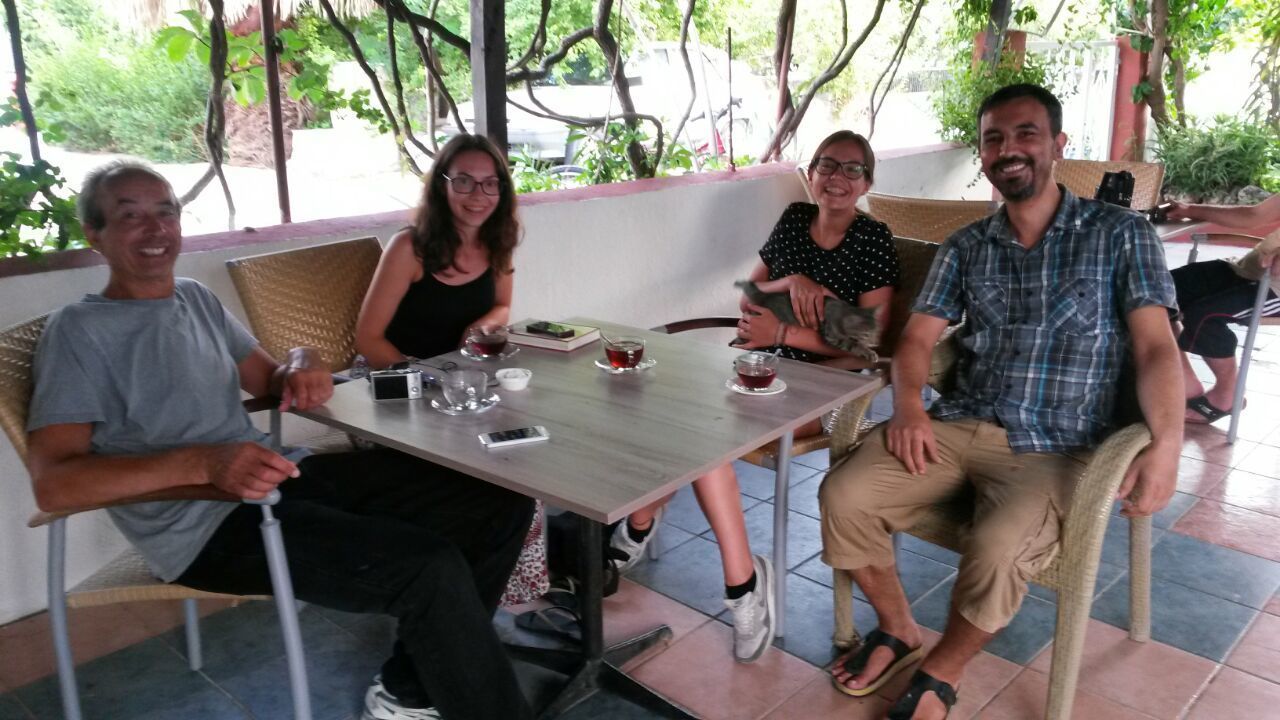 A group of people seated at an outdoor table with a view of greenery.