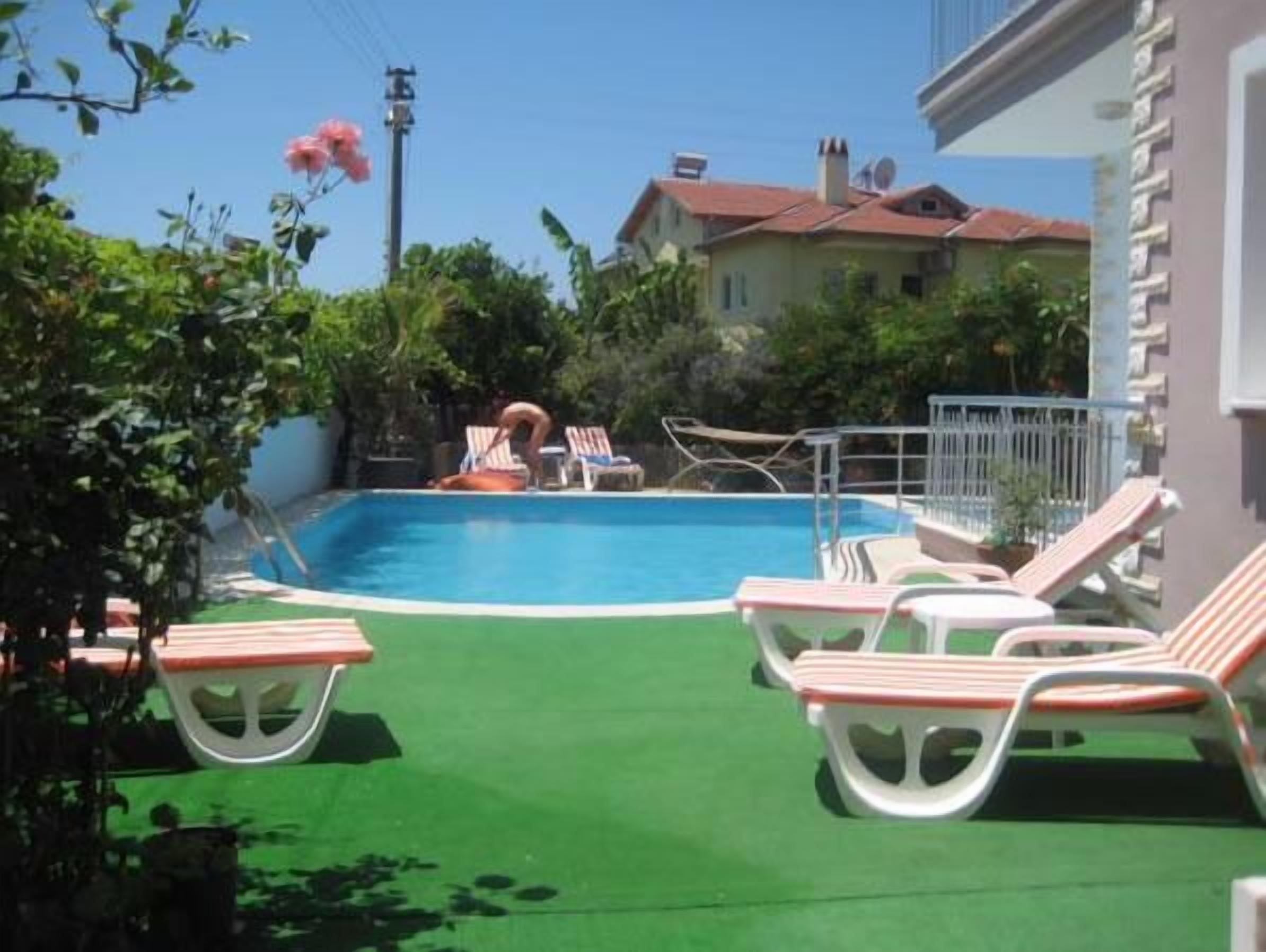 A swimming pool with lounge chairs and a diving board.